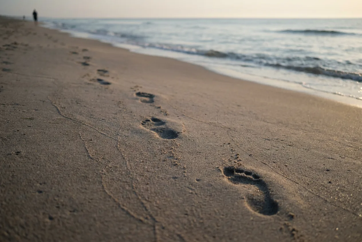 Fresh footprints on a beach at dawn
